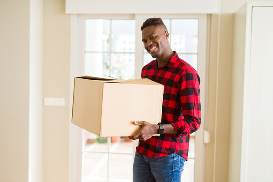 Young african american man holding a carton box, packing cardboard delivery package at home