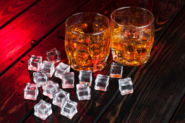 Two glasses of whiskey with ice cubes served on wooden planks.Studio photography