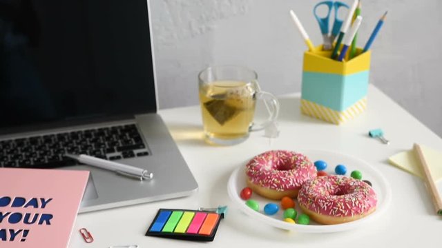 Zoom in on Work table with green plant in grey pot, notebook with an inscription Today is yor day! Laptop and doughnuts in home office studio. Freelance designer or blogger desktop. Wall Background,