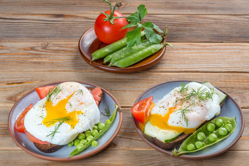 Top view of poached eggs with tomatoes and pees on wooden background.