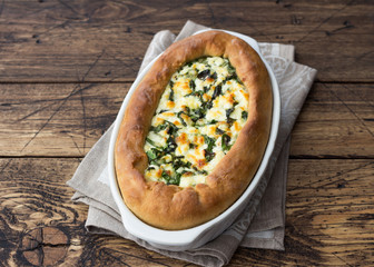 Open cheese pie with chard in Adjara style on the wooden table, top view. Delicious homemade food