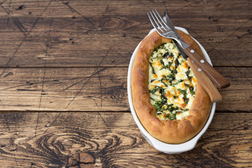 Open cheese pie with chard in Adjara style on the wooden table, top view. Delicious homemade food