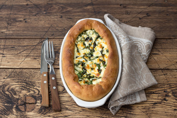 Open cheese pie with chard in Adjara style on the wooden table, top view. Delicious homemade food