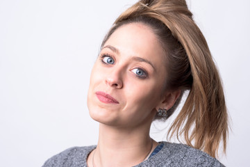 Fototapeta premium Close up portrait of young blue eyes cute woman with hair tied bun on light gray background. 