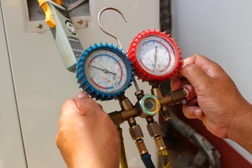 The technician is using tools to check the air conditioner, take a blur