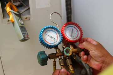 The technician is using tools to check the air conditioner, take a blur