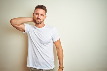 Young handsome man wearing casual white t-shirt over isolated background Suffering of neck ache injury, touching neck with hand, muscular pain