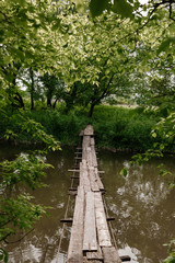 A small wooden bridge over a mild stream in a green park.