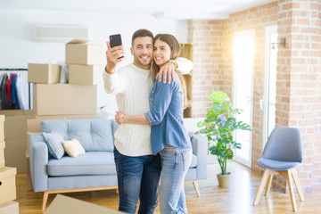 Fototapeta na wymiar Beautiful couple taking a selfie photo using smartphone at new apartment, smiling happy for new house