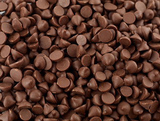 Chocolate morsels spread from top isolated on white background. Chocolate chips morsels.
