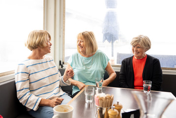 Three beautiful senior women enjoying retirement together having tea or coffee