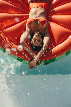 Woman sunbathing on inflatable mattress in pool