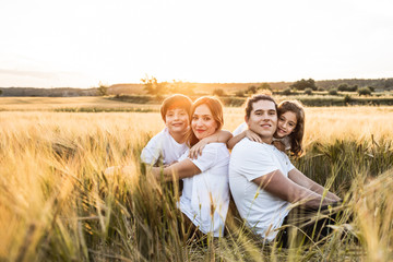 Naklejka na ściany i meble Funny happy family smiling in the field sunset