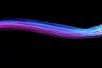 Long exposure, light painting photography.  Vibrant electric blue and neon pink streaks of colour against a black background