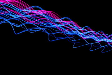 Long exposure, light painting photography.  Vibrant electric blue streaks and ripples of neon pink, against a black background
