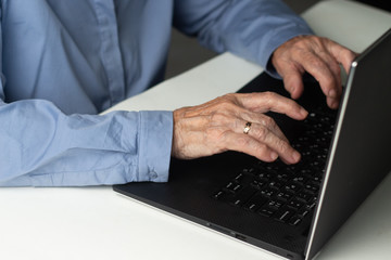 Senior gray-haired woman with laptop. Elderly woman writing memoirs on laptop, searching for information on the Internet or communicating online