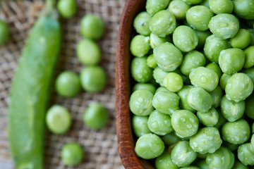 Fresh raw organic green peas (Pisum sativum) in wooden bowl. Top view