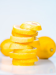 Naklejka na ściany i meble Composition of fresh yellow lemons on white background, close up view. Lemon cutted into slices on light desk. Pile of juicy slices. Blurred background. Selective soft focus
