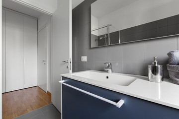 interior shot of a modern bathroom in the foreground the sink cabinet with built-in washbasin and steel tap