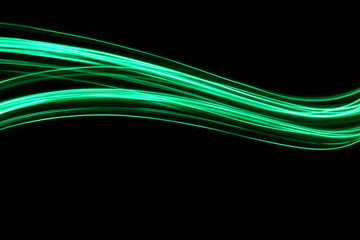 Long exposure, light painting photography.  Vibrant neon green streaks of colour against a black...
