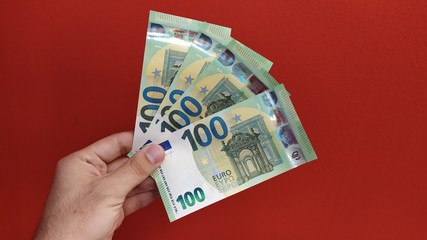Man holding new 100 euro banknotes released on 28 may 2019. Red background