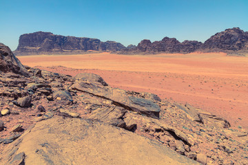 Fototapeta na wymiar Red sand desert at sunny summer day in Wadi Rum, Jordan. Middle East. UNESCO World Heritage Site and is known as The Valley of the Moon.