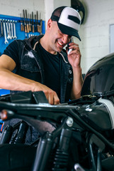 Mechanic talking on the phone while fixing the motorbike