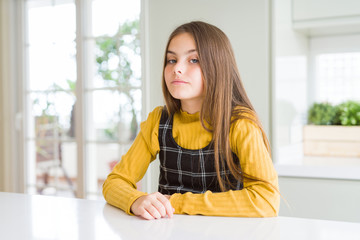 Young beautiful blonde kid girl wearing casual yellow sweater at home Relaxed with serious expression on face. Simple and natural looking at the camera.