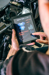 Mechanic reviewing motorcycle with a tablet app in the workshop