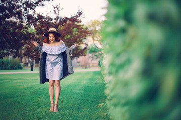 Fototapeta premium Red-haired model in a hat posing in a park