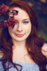 Naklejka premium Model with red hair posing in a blooming apple tree.