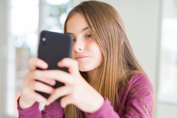 Beautiful young girl kid sending a message using smartphone with a confident expression on smart face thinking serious