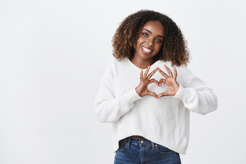 Love you guys. Attractive silly african-american woman afro hairstyle show heart gesture tilt head smiling joyfully express sympathy passion romantic attitude, standing white background carefree