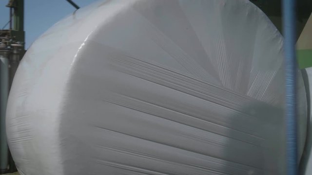 Machine is wrapping hay bales on the field