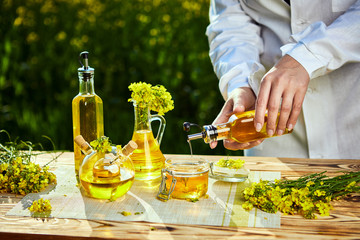rapeseed oil bottle in hand of an agronomist or biologist on background rape field