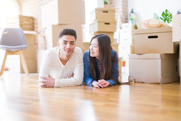 Fototapeta na wymiar Young asian couple lying on the floor of new house arround cardboard boxes relaxing and smiling happy