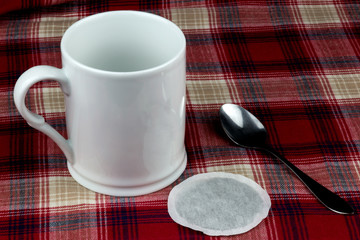 Mug Spoon and Tea Bag on a Plaid Table Cloth