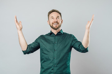 Fototapeta premium Joyful young man raising arms and looking up