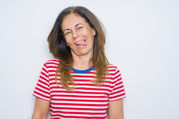 Middle age senior woman standing over white isolated background sticking tongue out happy with funny expression. Emotion concept.