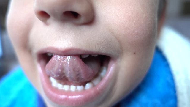 4K Child touches front milk teeth and upper lip with his tongue