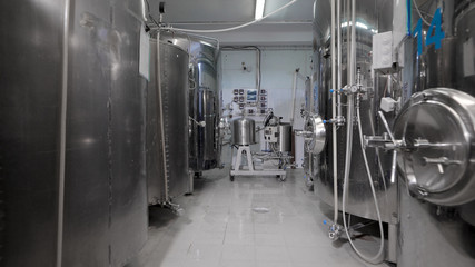 Fototapeta na wymiar fermentation vats are standing in clean shop of modern brewery in working day, camera is moving back