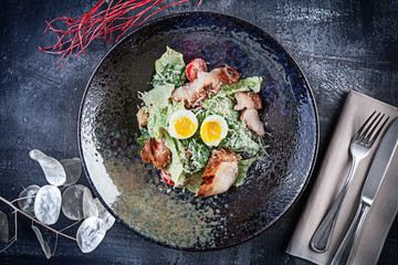 Top view on fresh salad bowl served on dark stone background. Flat lay food for lucnh with copy space. Picture for menu. Modern Caesar salad