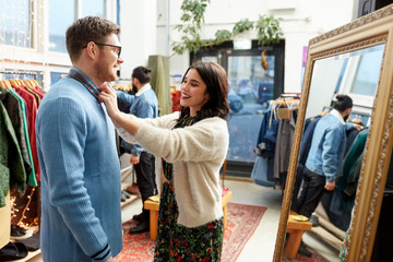 Obraz premium sale, shopping, fashion and people concept - couple choosing clothes at vintage clothing store