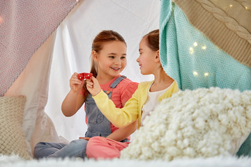 childhood and hygge concept - happy little girls playing tea party with toy crockery and clinking cups in kids tent at home © Syda Productions