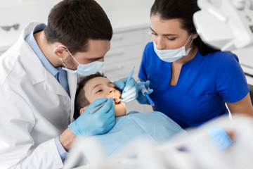 Medizin-, Zahn- und Gesundheitskonzept - Zahnarzt mit Mundspiegel und Sonde, die in der Zahnklinik auf die Zähne von Kinderpatienten überprüft