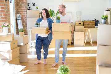 Fototapeta na wymiar Young couple moving to a new home, smiling happy holding cardboard boxes