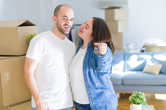 Young couple smiling very happy showing keys of new home, moving and buying new apartmet concept