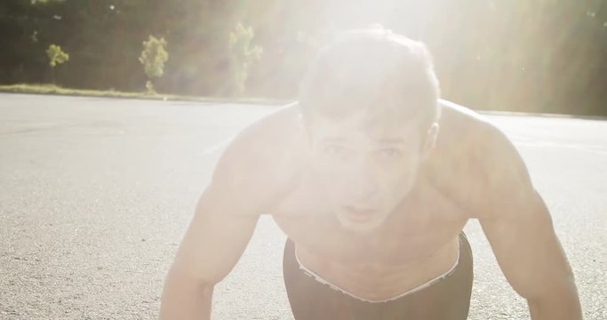 Handsome male athlete having intense workout outdoors, warming up before running.