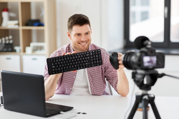 blogging, videoblog and people concept - male blogger with camera recording video review of keyboard and computer mouse at home office