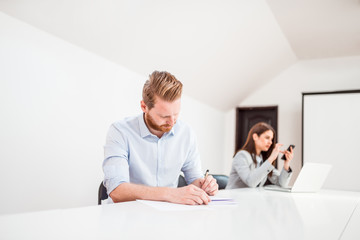 Obraz premium Redhead entrepreneur handwriting in bright meeting room.